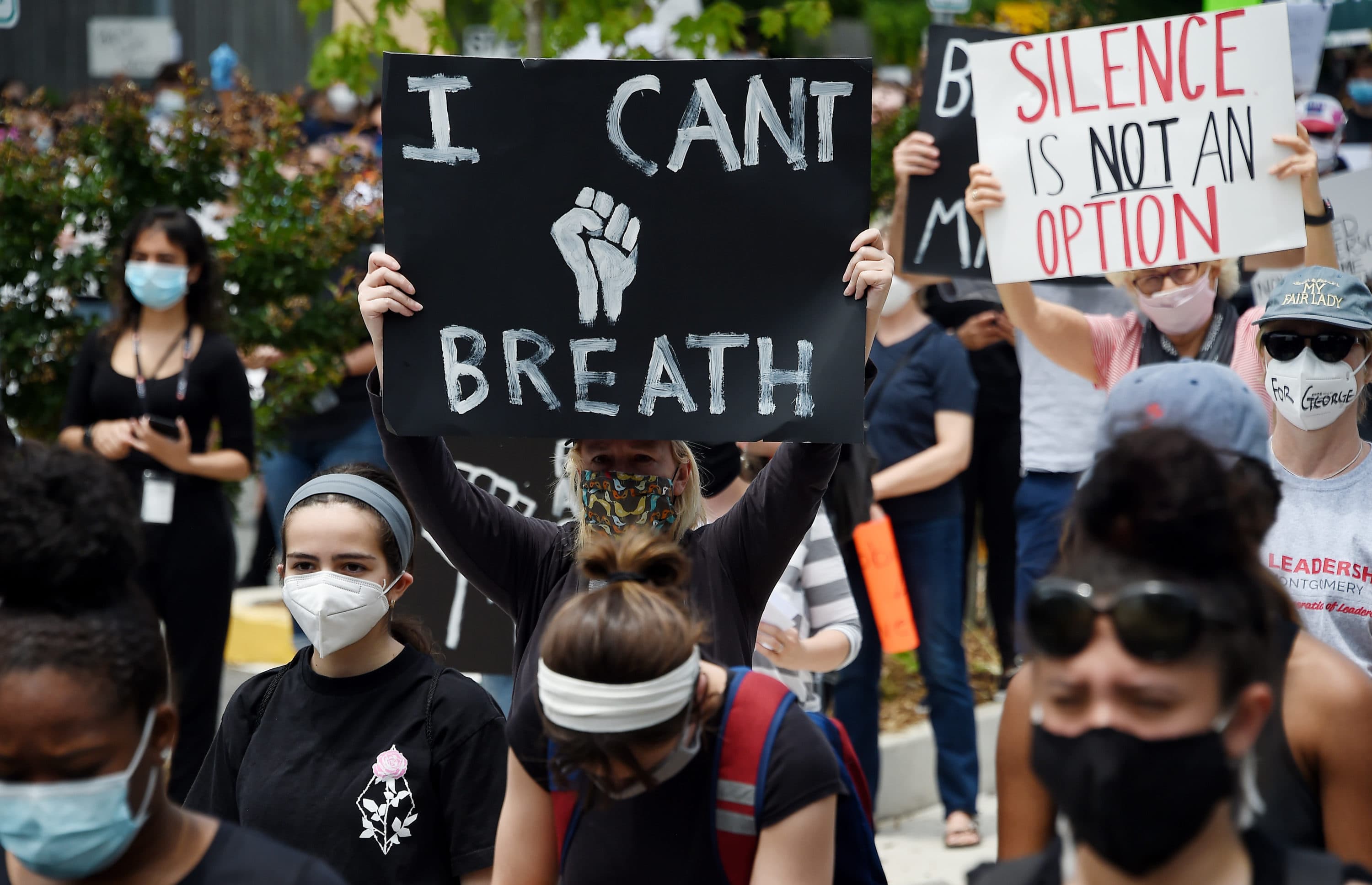 Peaceful demonstrators hold signs as they protest the death of George Floyd outside the Bethesda Library on June 2, 2020 in Bethesda, Maryland. (Olivier Douliery/AFP via Getty Images)