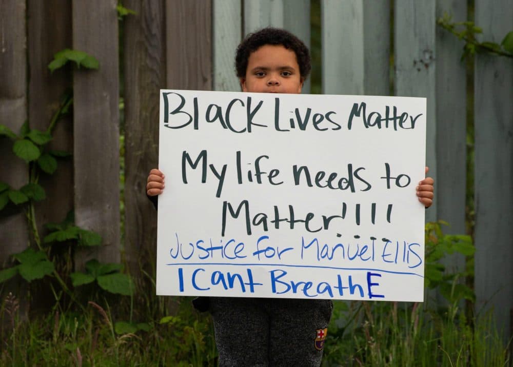 A boy holds a sign during a vigil for Manuel Ellis, a black man whose March death while in Tacoma Police custody was recently found to be a homicide, near the site of his death on June 3, 2020 in Tacoma, Washington. (David Ryder/Getty Images)