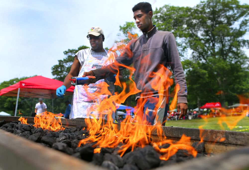 Ralph Johnson, left, and his nephew John Jackson Jr light the charcoal fire on his grill during a Juneteenth celebration at the Franklin Park Playstead in the Dorchester neighborhood of Boston on June 16, 2018. (John Tlumacki/The Boston Globe via Getty Images)