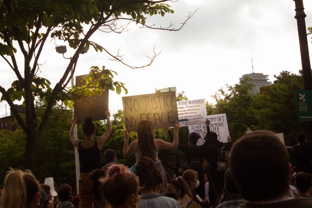 Peaceful protestors hold signs during a protest in Boston on Friday, May 29, 2020 (Arielle Gray/WBUR)