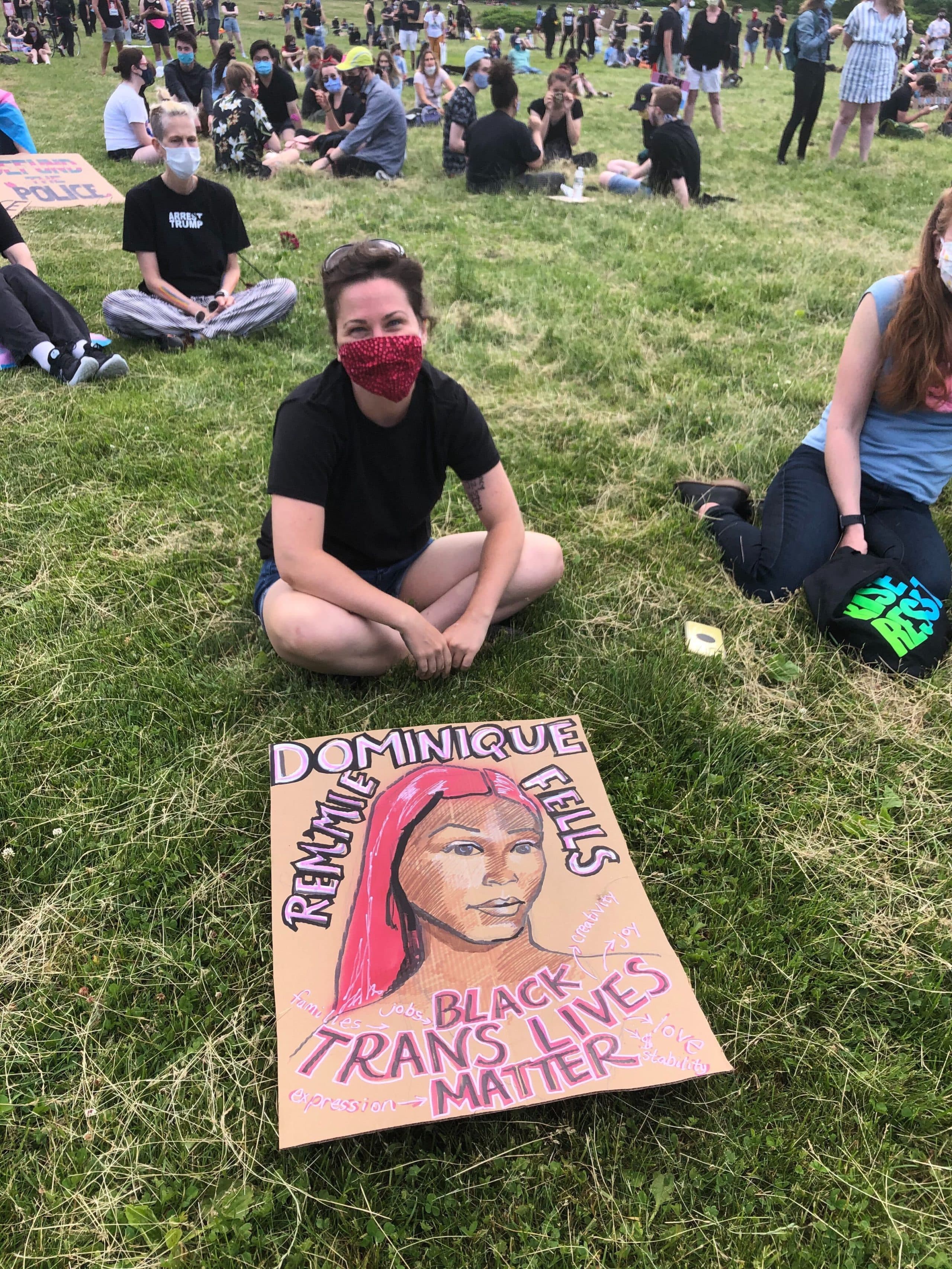 A protestor sits with a sign honoring Dominique "Rem'mie" Fells, a transgender woman murdered in Philadelphia, Penn., on June 9. (Cristela Guerra/WBUR)
