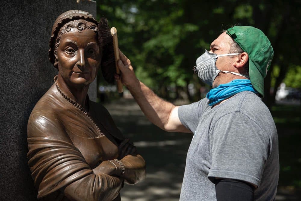 Sculpture conservator Joshua Craine completes the cleanup of the Abigail Adams statue at the Boston Women’s Memorial on Commonwealth Avenue Mall. (Robin Lubbock/WBUR)
