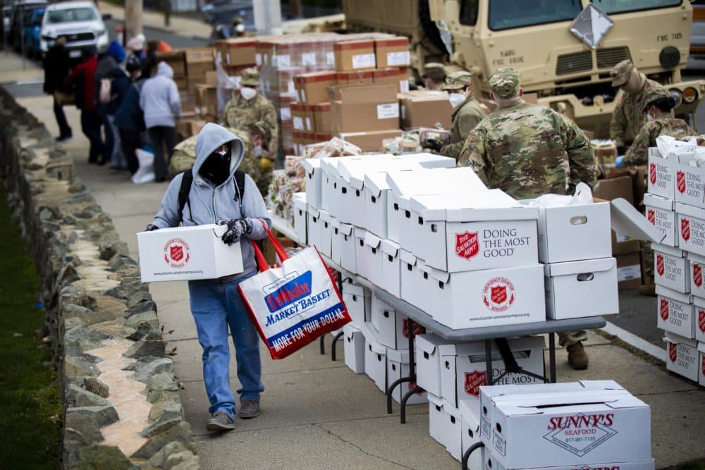 A Chelsea resident carries a box of food supplies during a pop-up food pantry at Washington Park in April. (Jesse Costa/WBUR)