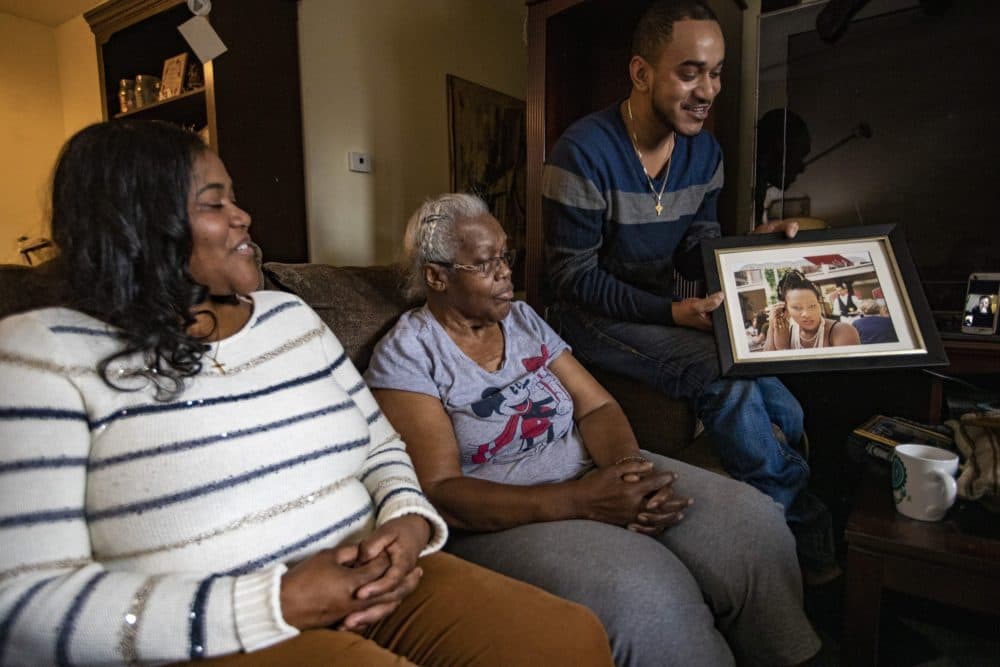 Sister Diana Hester and mother Kathleen Hester look as nephew Taufiqul Chowdhury shows a photograph of Rita Hester as they reminisce about her. (Jesse Costa/WBUR)
