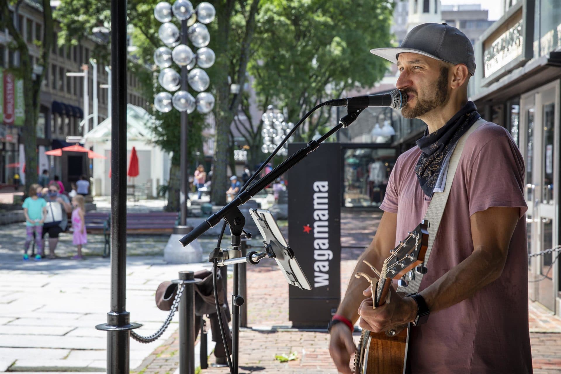 Guitarist and singer Ryan LaPerle plays for a small but appreciative audience as Faneuil Marketplace officially reopens. (Robin Lubbock/WBUR)
