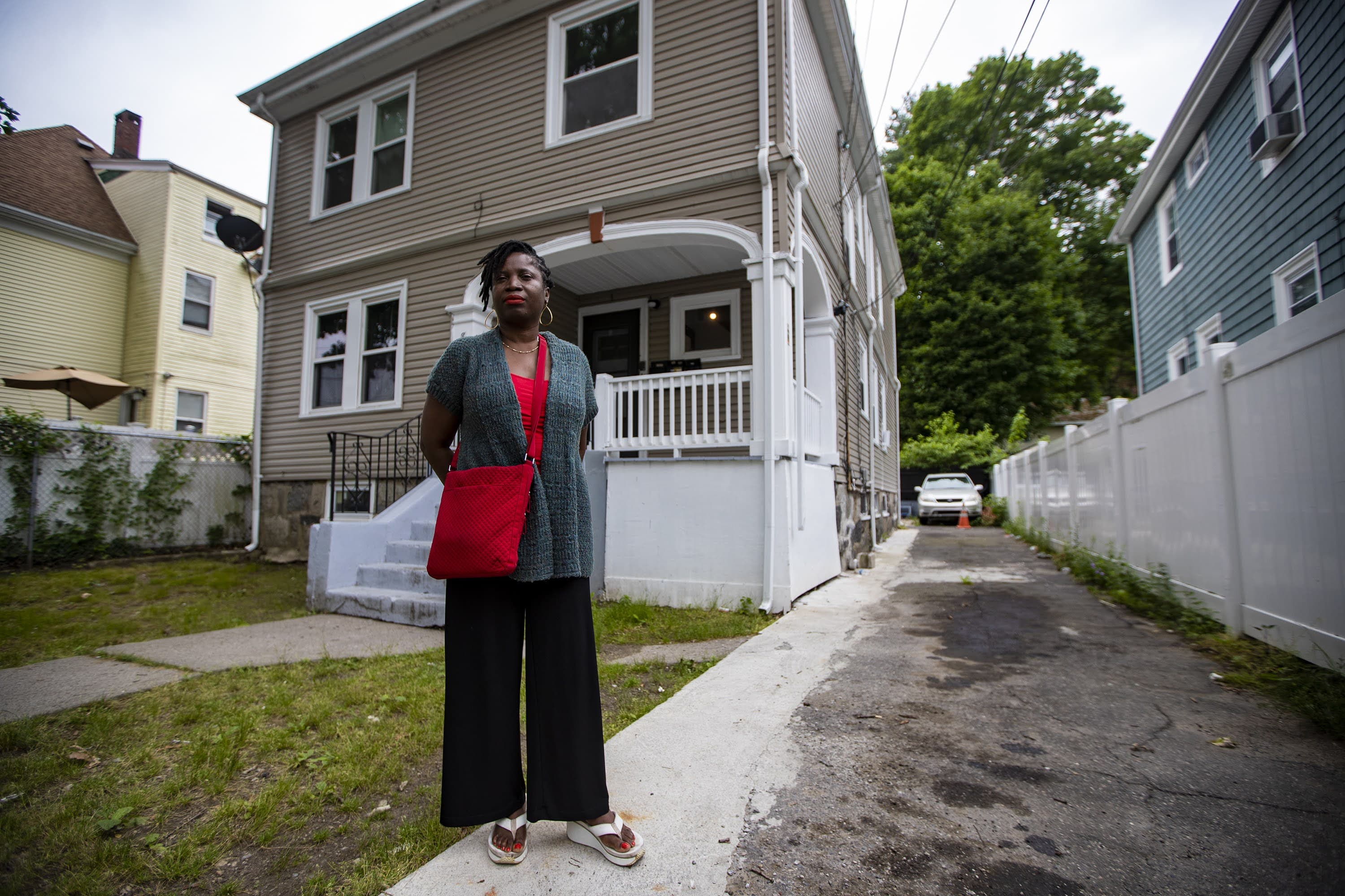 Carline Chery stands outside of her rental property in Dorchester. (Jesse Costa/WBUR)