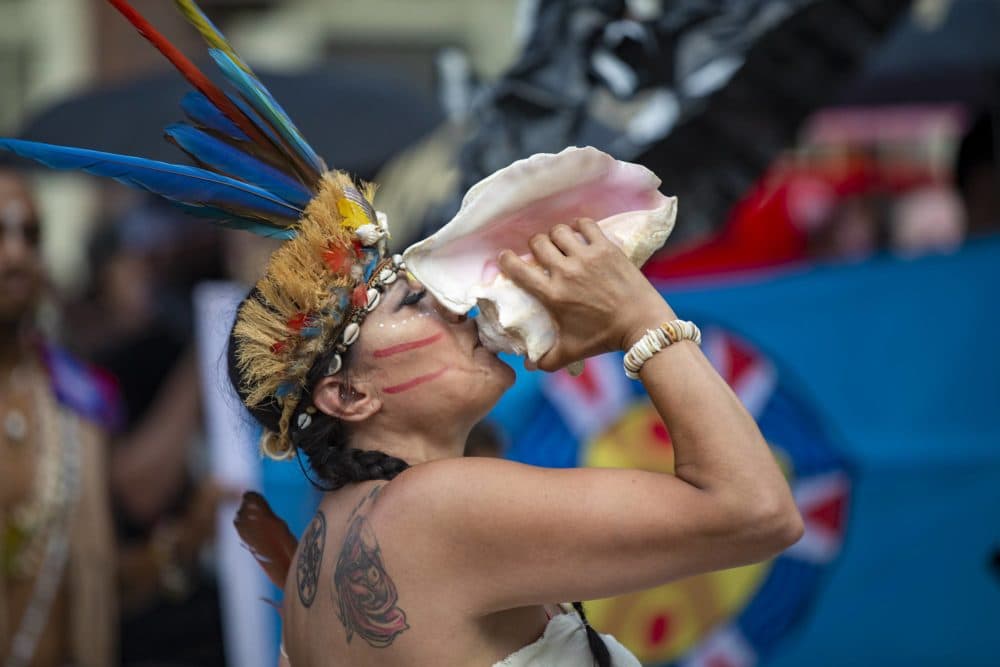 Chali’Naru Dones of the United Confederation of Taino People blows through a conch to signal the beginning of the march to Boston City Hall. (Jesse Costa/WBUR)