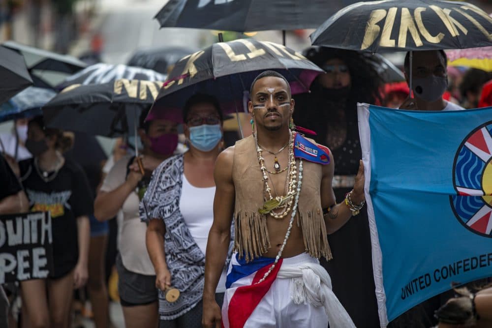 Protesters march down Congress Street with umbrellas towards City Hall Plaza during the Dismantle Now! BIPOC Solidarity Against White Supremacy: March + Art Action. (Jesse Costa/WBUR)