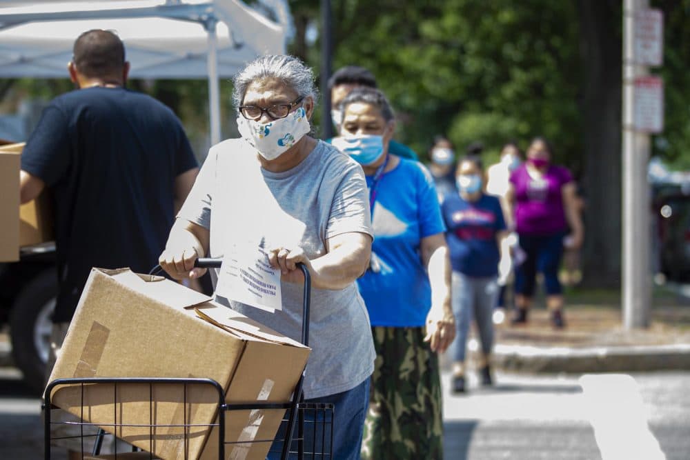 A long line of Chelsea residents receive boxes of food supplies at a food pantry in Chelsea Square. (Jesse Costa/WBUR)