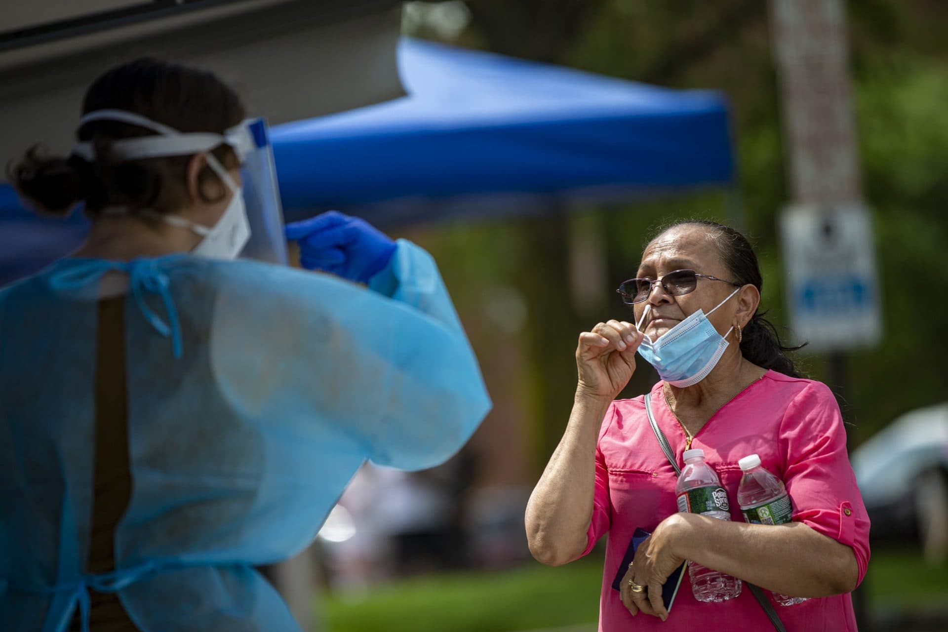 A Chelsea resident is being directed by a healthcare worker before inserting a swab up her nose during free COVID-19 testing offered by the state in Chelsea Square. (Jesse Costa/WBUR)