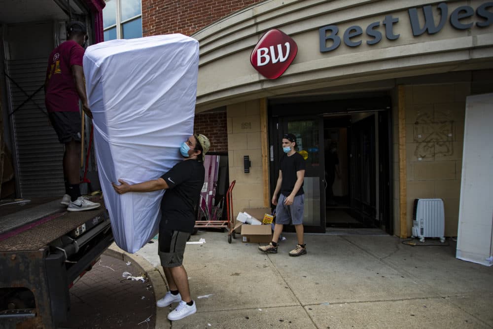 Movers unload mattresses from a truck into the Best Western Hotel on Massachusetts Avenue in Boston. Pine Street is leasing the property near Boston Medical Center as part of a plan to avoid shelter overcrowding ahead of another potential surge of the coronavirus. (Jesse Costa/WBUR)