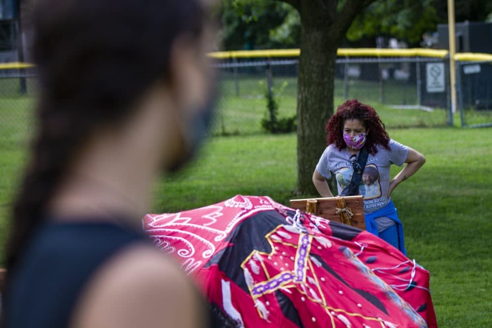 Diana Bernard reads the &quot;South - Learning&quot; plaque, a part of the Lilly Manycolors art installation “The Red Dress Lodge” as the artist looks on. The art installation is meant to bring awareness of murdered and missing indigenous womxn and girls and is on display at the Boston Common. (Jesse Costa/WBUR)