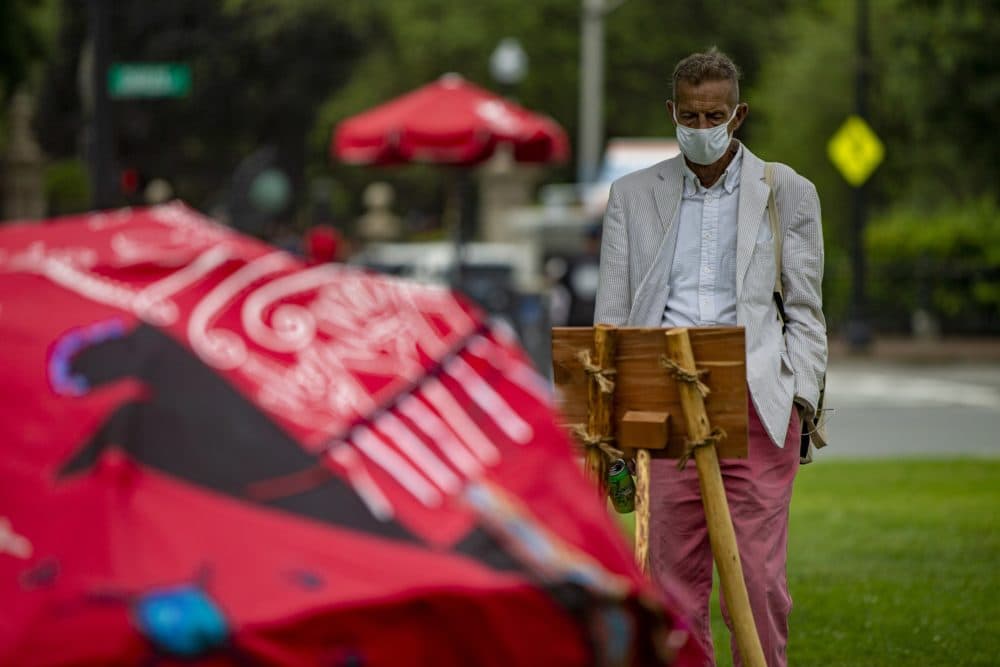 Donald Aucoin, visiting from Washington DC, reads the “East - Beginning” plaque of the Lilly Manycolors art installation “The Red Dress Lodge” on display at the Boston Common. (Jesse Costa/WBUR)