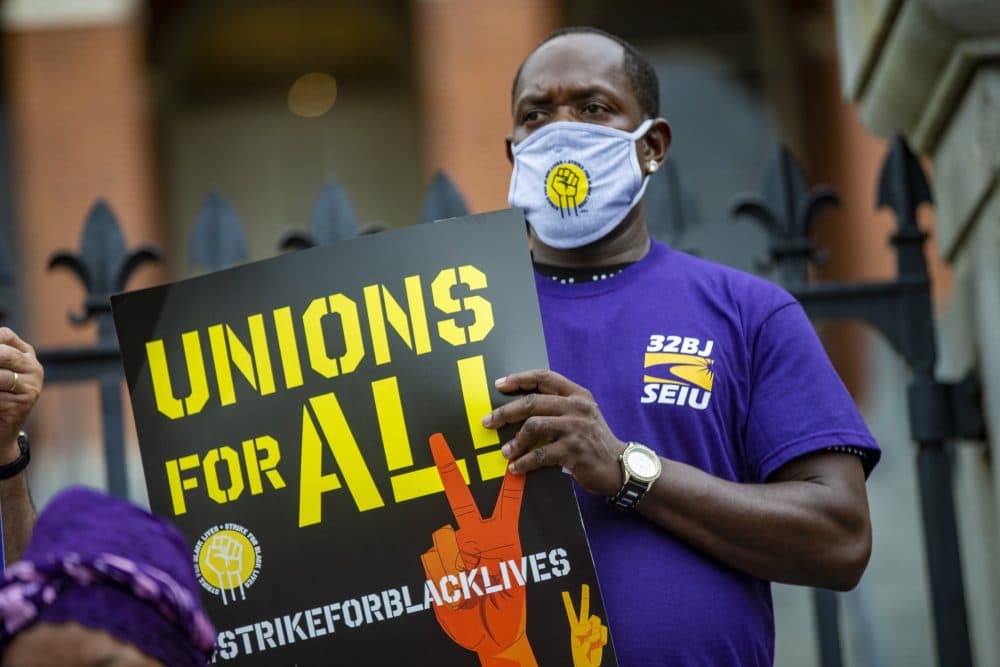 A member of SEIU 32BJ holds a sign during the Strike for Black Lives rally in front of the State House in Boston on Monday. (Jesse Costa/WBUR)