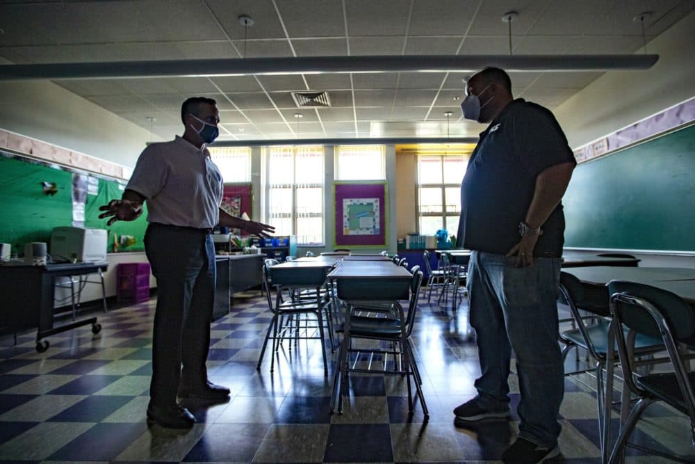 Somerville Mayor Joseph Curtatone reviews seating arrangements in a classroom with the supervisor of facilities Michael Bowler at West Somerville Community School. (Jesse Costa/WBUR)