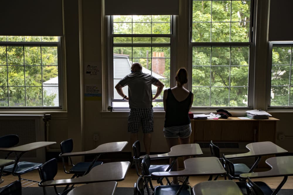 Matthew Gillis , director of operations at Brookline Public Schools, checks a window while volunteer parent Kristin Jones records the window is working properly. at the Old Lincoln School in Brookline. (Jesse Costa/WBUR)