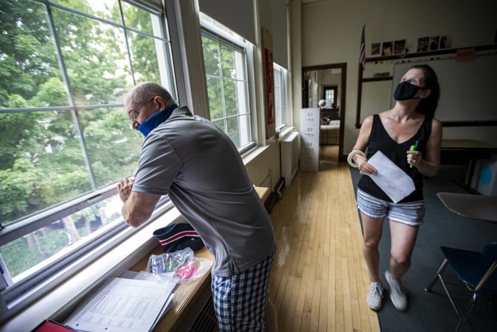 Matthew Gillis, director of operations for the Brookline school district, and volunteer parent Kristin Jones check the windows are working properly at the Old Lincoln School in Brookline. (Jesse Costa/WBUR)