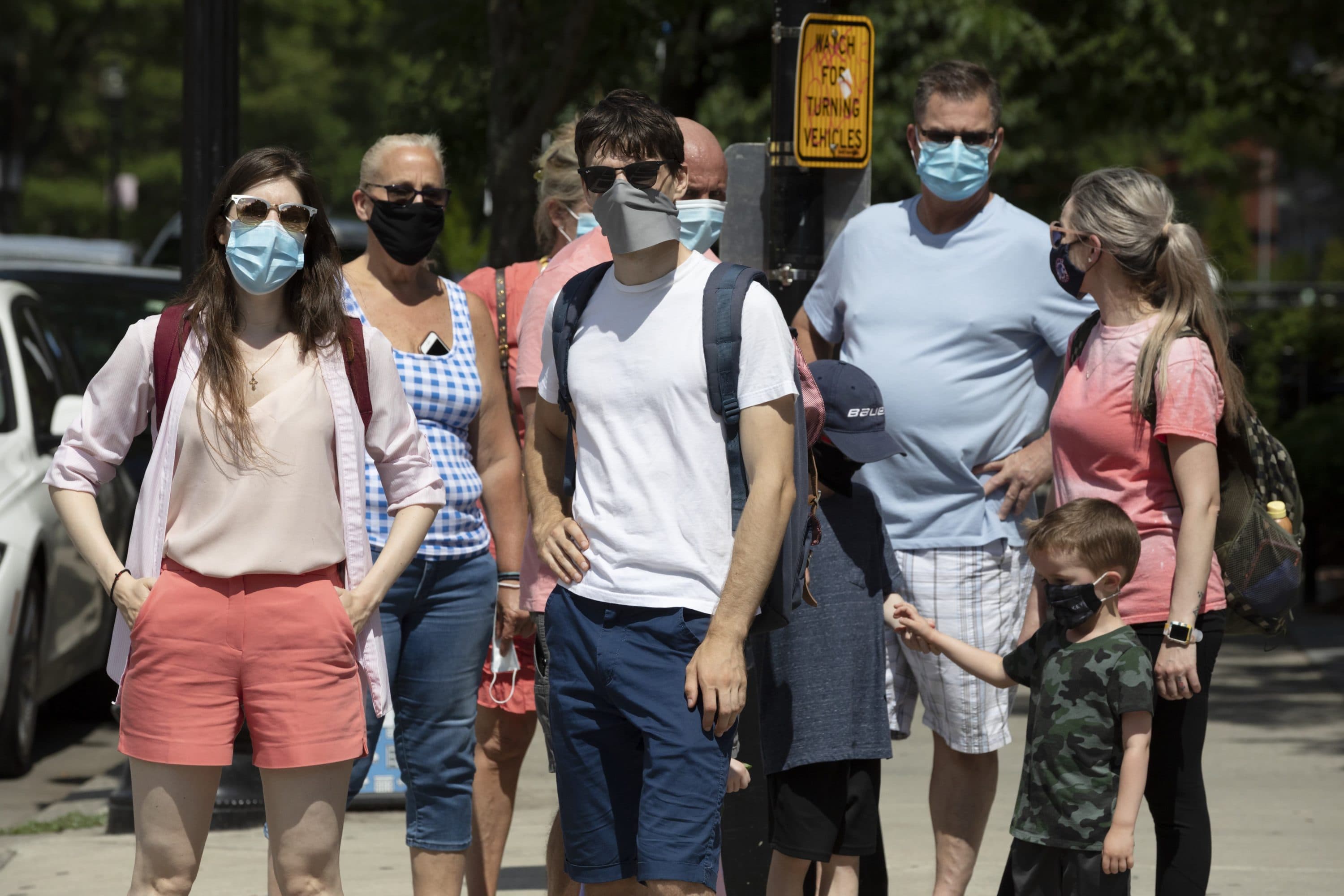 People wearing protective masks stand on the corner during a busy day on Newbury Street, July 11, 2020, in Boston. (Michael Dwyer/AP)