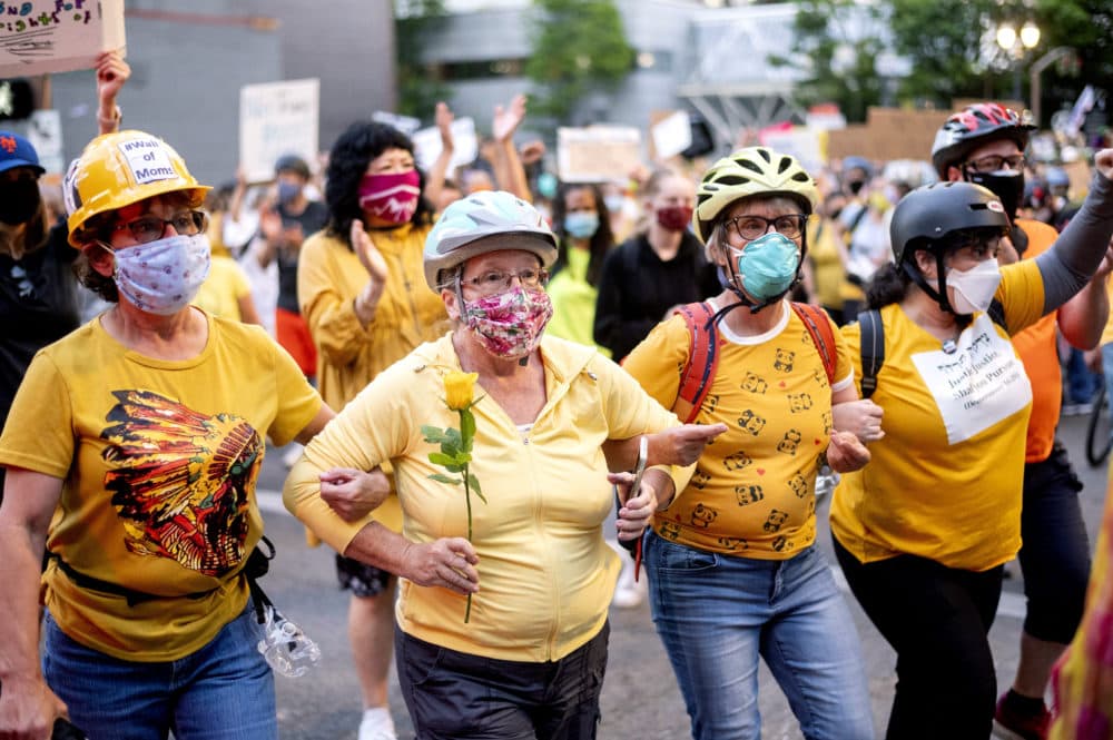 Norma Lewis holds a flower while forming a "wall of moms" during a Black Lives Matter protest on Monday, July 20, 2020, in Portland, Ore. (Noah Berger/AP)
