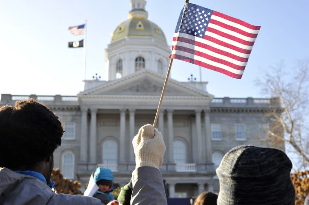 A man waves a U.S. flag outside the New Hampshire State House. (Joseph Prezioso/AFP via Getty Images)