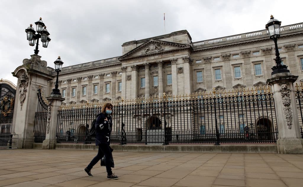 A woman wearing a face mask as a precautionary measure against COVID-19 walks outside Buckingham Palace in London. (Tolga Akmen/AFP/Getty Images)