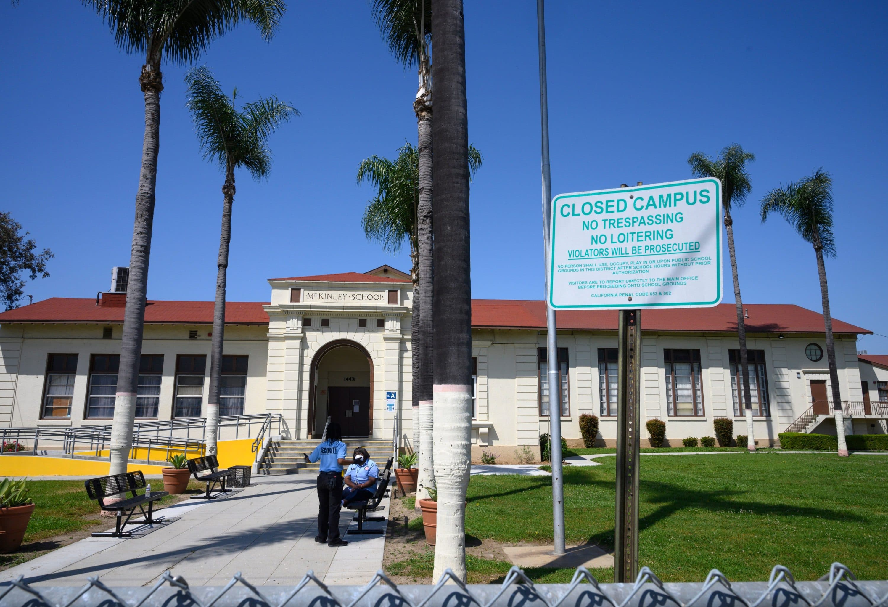 Two security guards talk on the campus of the closed McKinley School, part of the Los Angeles Unified School District (LAUSD) system, in Compton, California. (Robyn Beck/AFP via Getty Images)