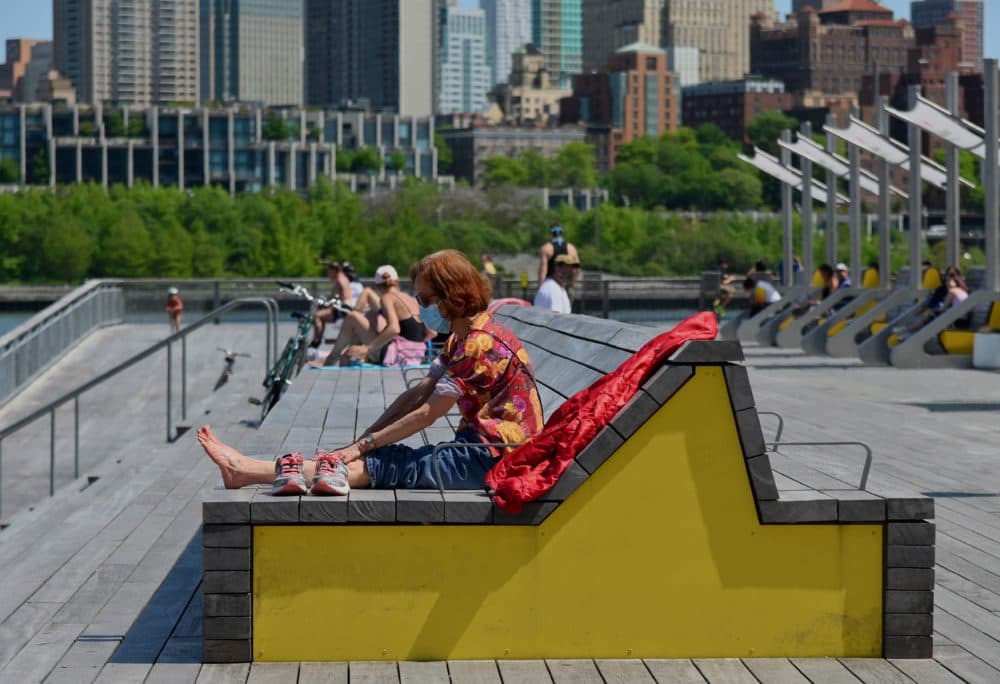 A woman wearing a face mask relaxes in the sun on May 26, 2020 in New York City. (Photo by Angela Weiss /Getty AFP)