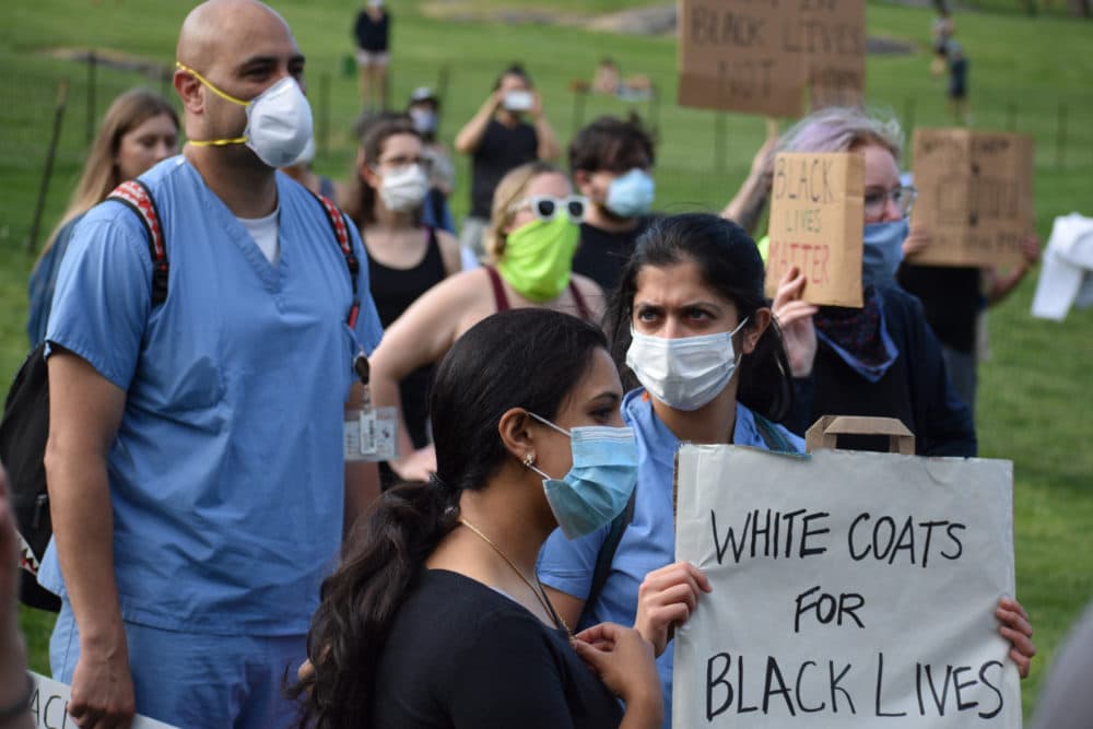 Medical workers in face masks hold signs during a rally organized by a group named White Coats for Black Lives in Central Park on June 6, 2020. (Maria Khrenova/Getty Images)