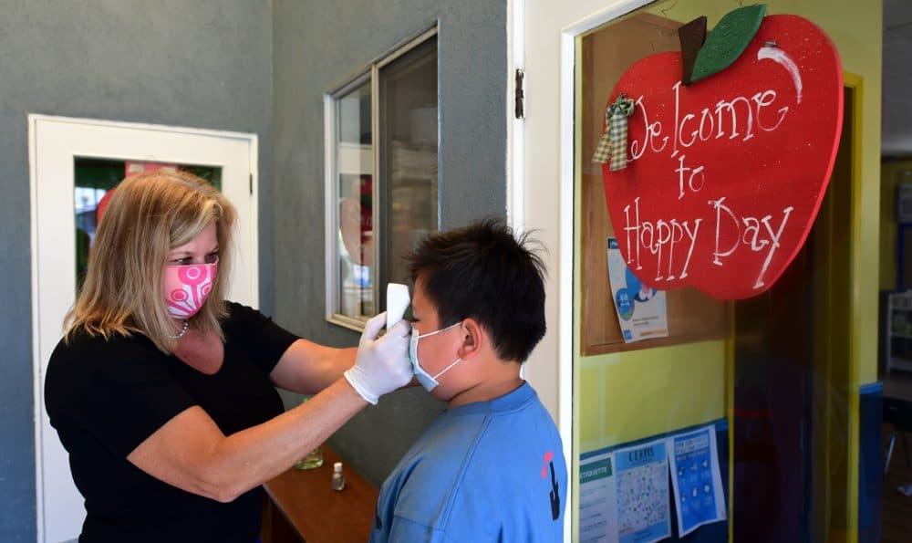 Principal Pam Rasmussen checks the temperature of students on arrival as per coronavirus guidelines, during summer school sessions at Happy Day School in Monterey Park, California on July 9, 2020. (Frederic J. Brown/AFP via Getty Images)