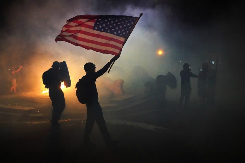 A protester flies an American flag while walking through tear gas fired by federal officers during a protest in front of the Mark O. Hatfield U.S. Courthouse on July 21, 2020 in Portland, Ore. The federal police response to the ongoing protests against racial inequality has been criticized by city and state elected officials. (Nathan Howard/Getty Images)