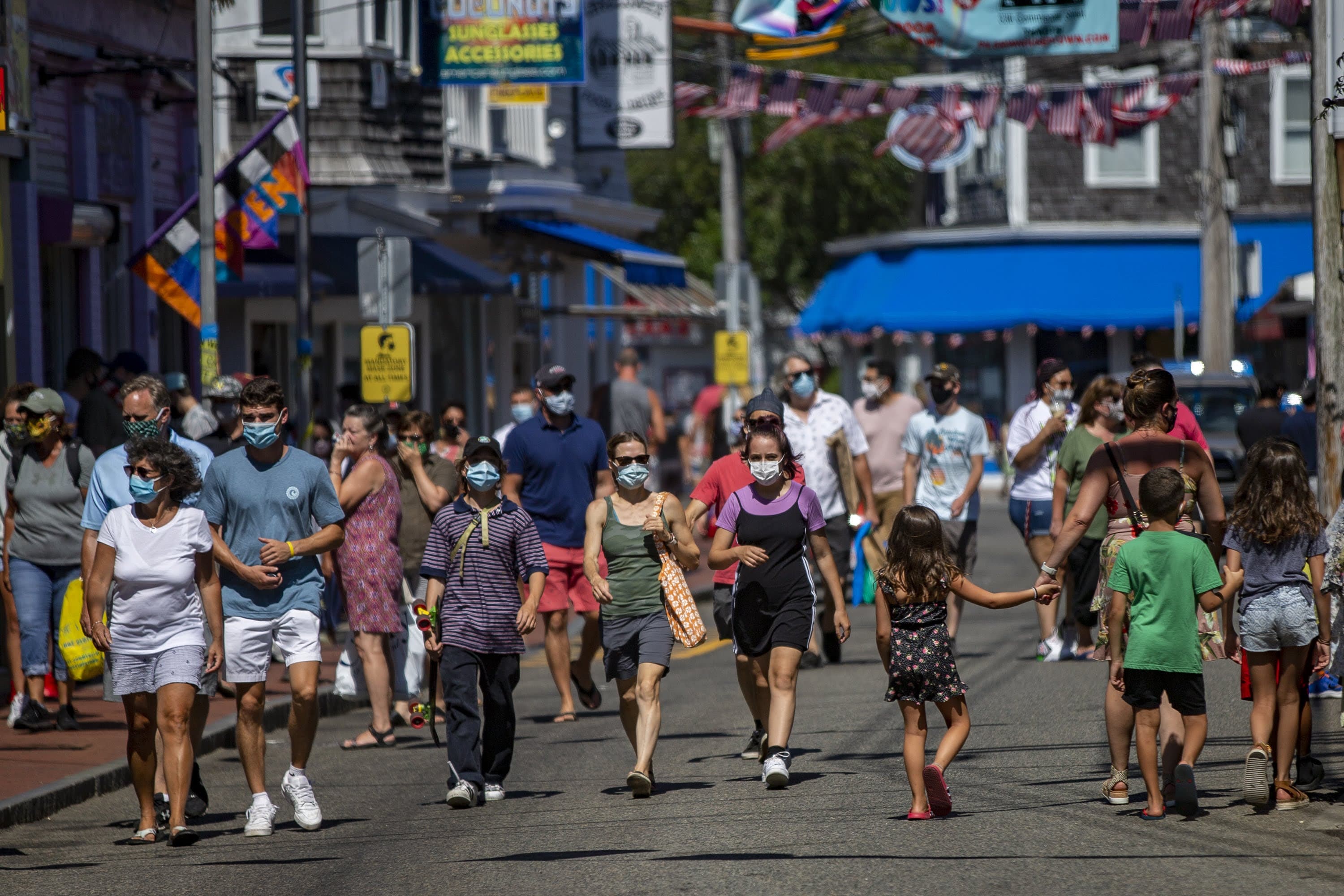 Tourists walk along Commercial Street in Provincetown, an area where local officials ordered it mandatory to wear a mask in the business district due to the coronavirus pandemic. (Jesse Costa/WBUR)