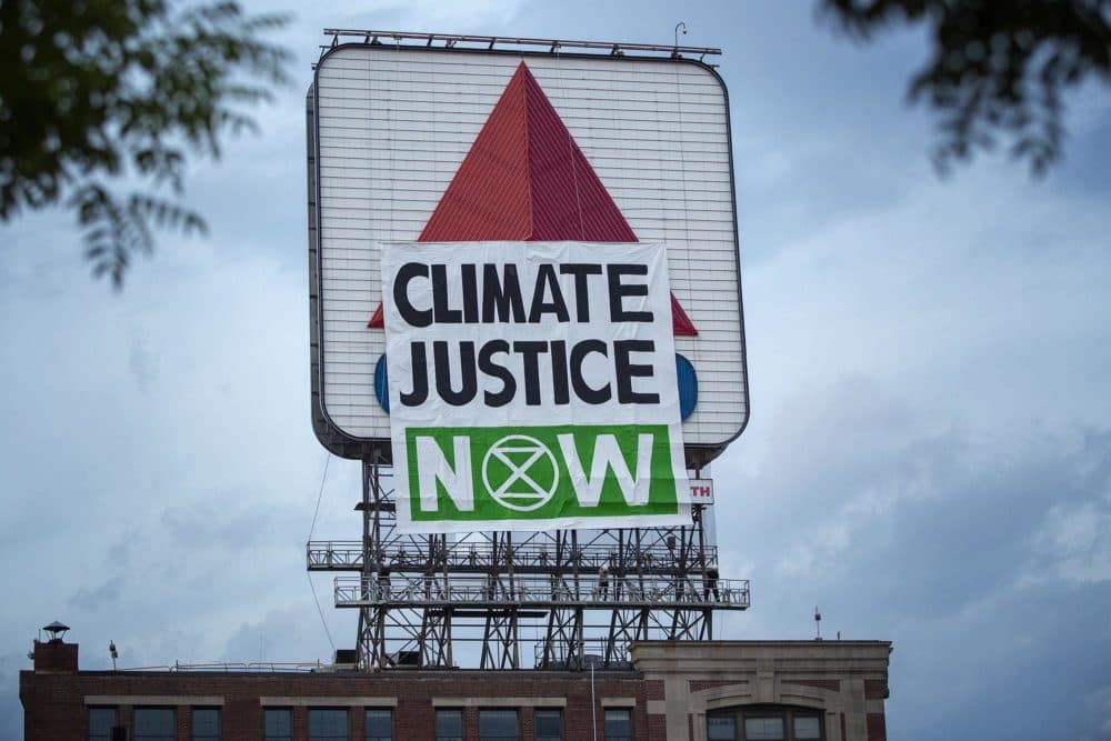 Activists from Extinction Rebellion raised a banner on the side of the Citgo sign facing Fenway Park which read &quot;Climate Justice Now&quot; on Monday evening. While the activists were still pulling up the sign the wind appeared to snap the bar holding the banner straight, causing it to collapse.. (Robin Lubbock/WBUR)