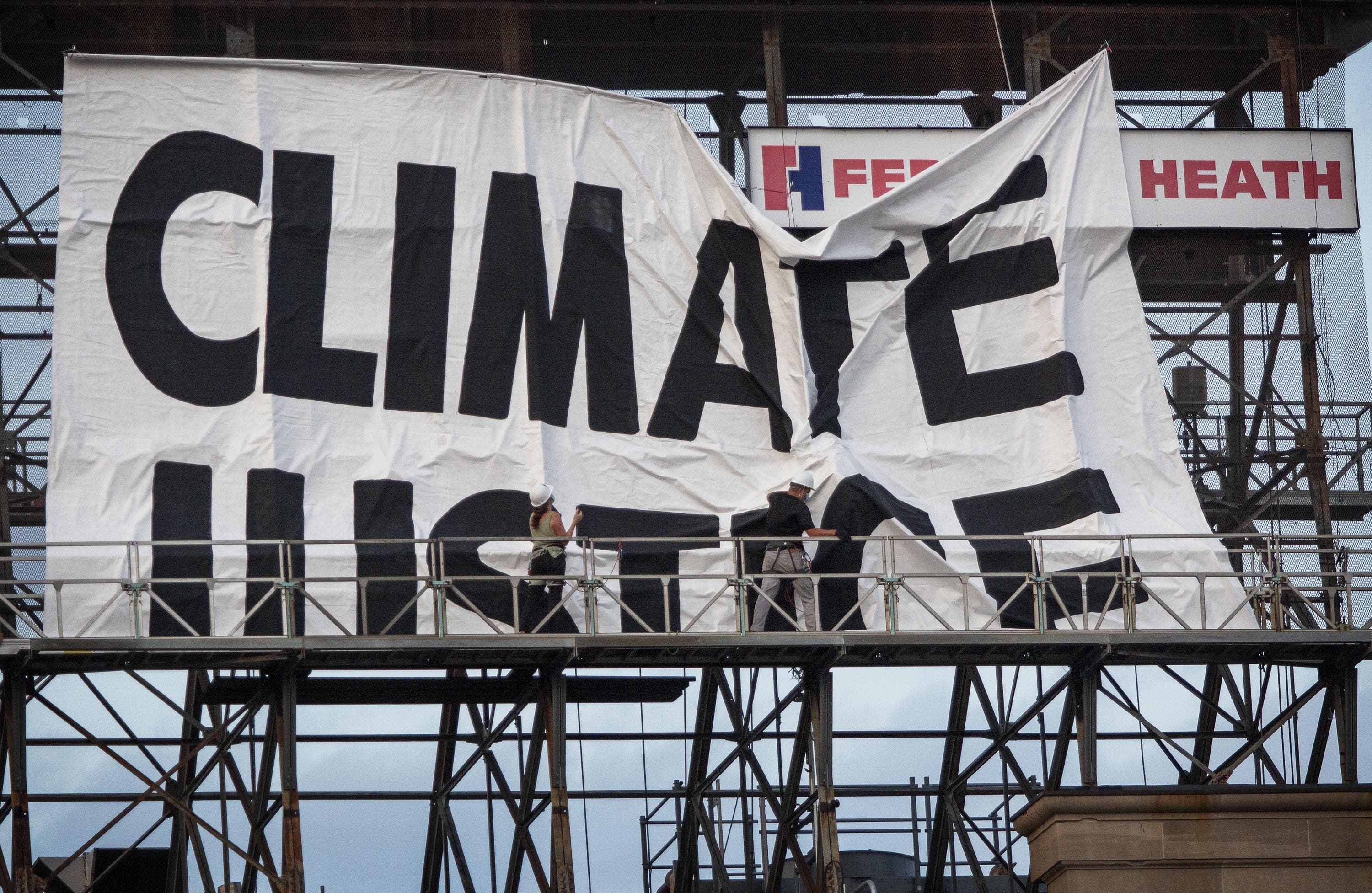 As the evening Red Sox game is about to begin, activists from Extinction Rebellion start to raise a banner on the Citgo sign in Kenmore Square, Boston. (Robin Lubbock/WBUR)