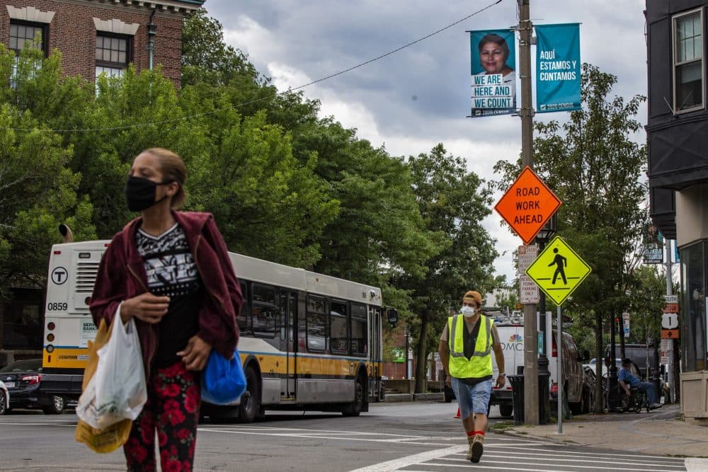Banners reading “Aquí estamos y contamos” or “We are here and we count” hang on the lamp posts in Bellingham Square encouraging rall esidents of Chelsea to fill out the 2020 Census. (Jesse Costa/WBUR)