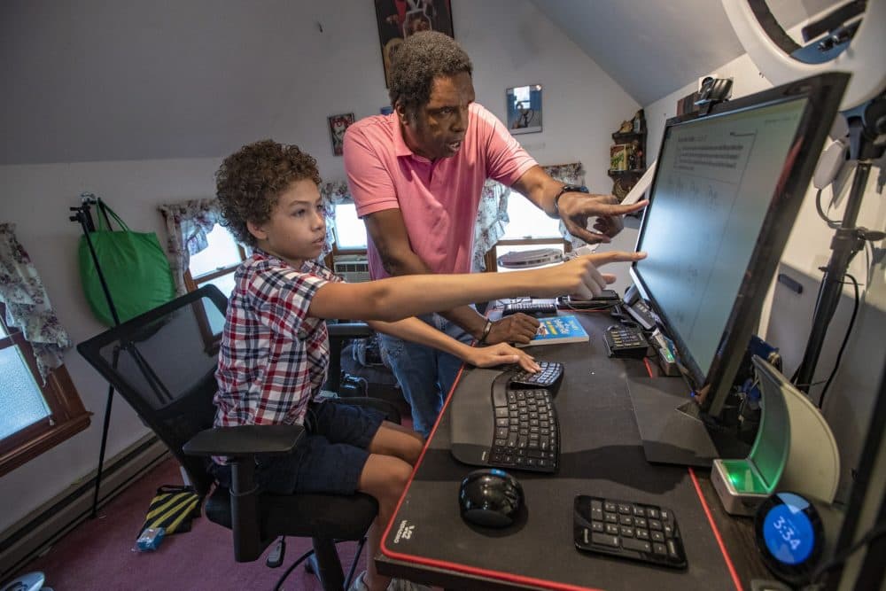 Orman Beckles does math problems on the computer at home with his 11-year old son Mikk. Beckles lives in Malden with his son, wife, and elder mother. He is glad that district is starting remote. (Jesse Costa/WBUR)