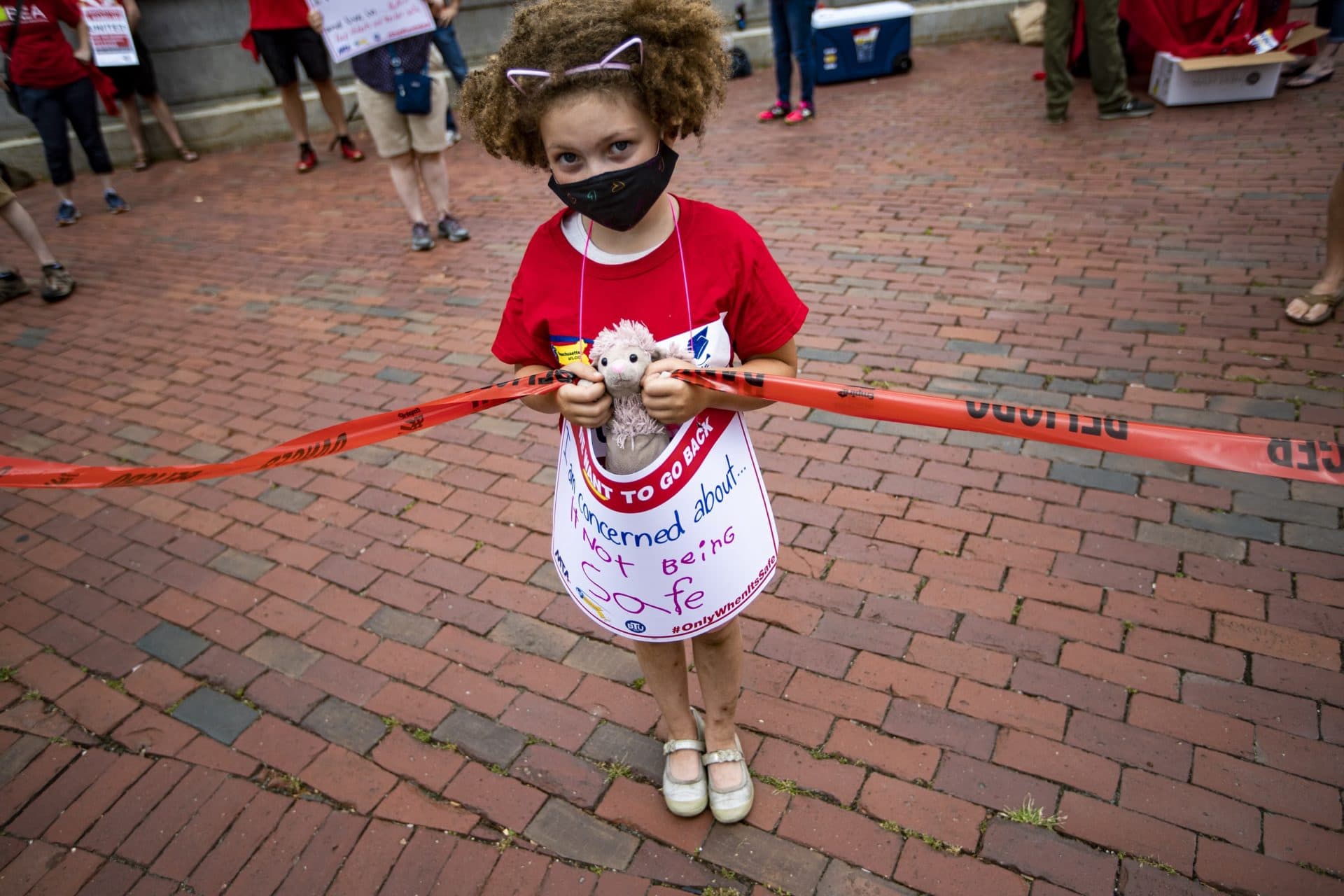 Ella James Burg Power, 7, of Worcester holds a sign that reads “I’m concerned about not being safe” during a rally demanding Gov. Charlie Baker to safely reopen schools being held by the Massachusetts Teachers Union at the State House. (Jesse Costa/WBUR)