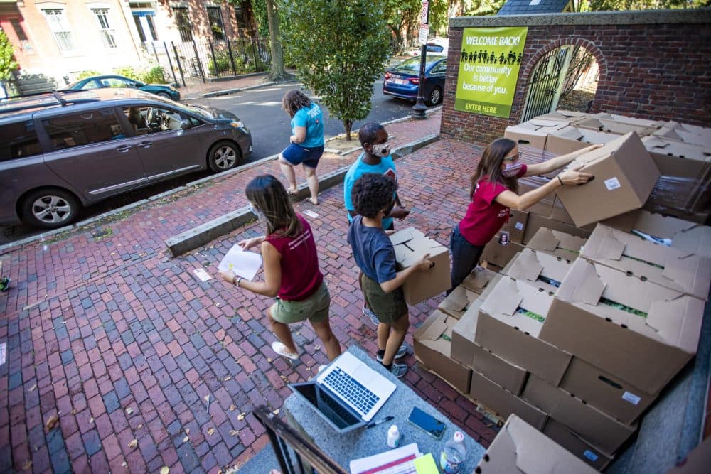 For families whose children are enrolled in the summer program, workers at the United South End Settlements carry boxes of food supplies to the vehicles of parents picking up their children at the end of the day. (Jesse Costa/WBUR)