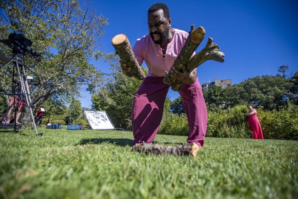 Omar Robinson, as Ferdinand, picks up logs during a rehearsal for a scene in &quot;The Tempest&quot; at the Arnold Arboretum, one of a series of selected scenes, sonnets and monologues by the Actors' Shakespeare Project called &quot;The Nature of Shakespeare.&quot; (Jesse Costa/WBUR)