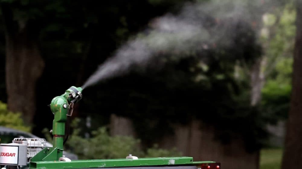A vapor, sprayed to control mosquitos, hangs airborne as it leaves the nozzle of an East Middlesex Mosquito Control Project pick-up truck on July 8, 2020, while driving through a neighborhood in Burlington, Mass. (Charles Krupa/AP)