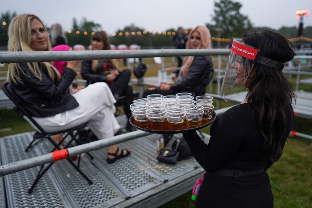 A waitress walks between socially distanced enclosures selling drinks to fans ahead of Sam Fender performing at the Virgin Money Unity Arena on Aug.13, 2020 in Newcastle upon Tyne, England. (Ian Forsyth/Getty Images)