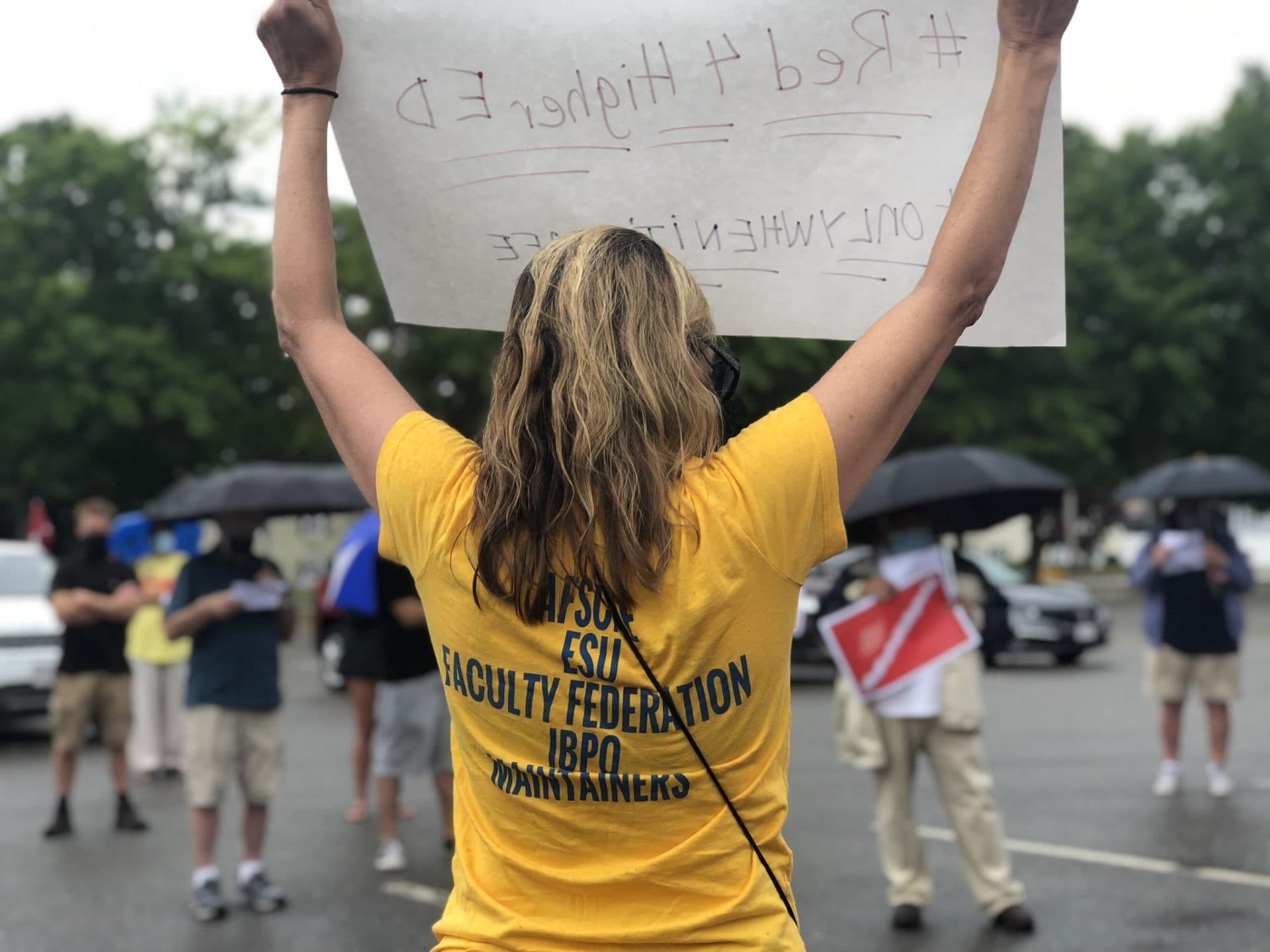 A protester holds a sign outside of Bristol Community College in Fall River. (Max Larkin/WBUR)