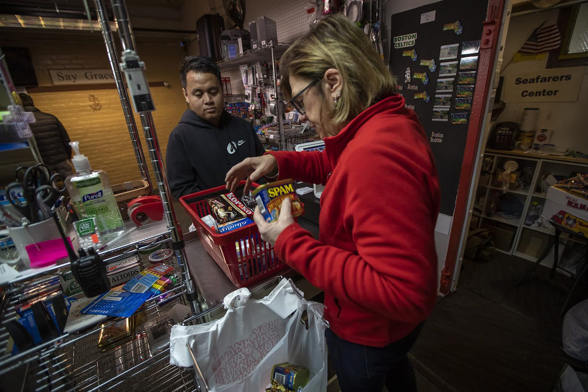 A cashier rings a cruise ship worker out inside the tiny convenience store. (Jesse Costa/WBUR)
