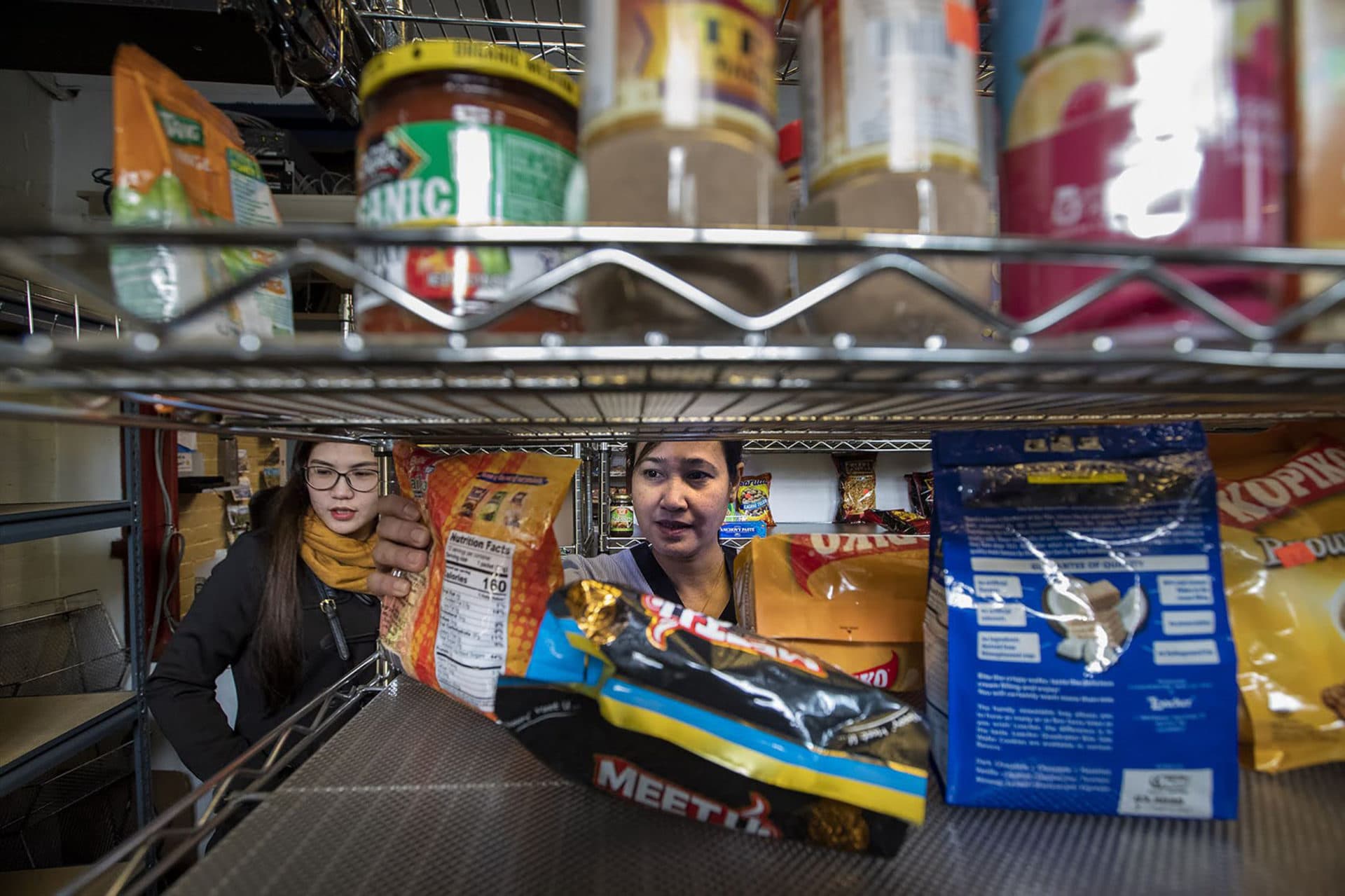 A woman grabs a bag of instant Thai tea from a shelf of many different imported items for sale at the Seafarers Mission store. (Jesse Costa/WBUR)