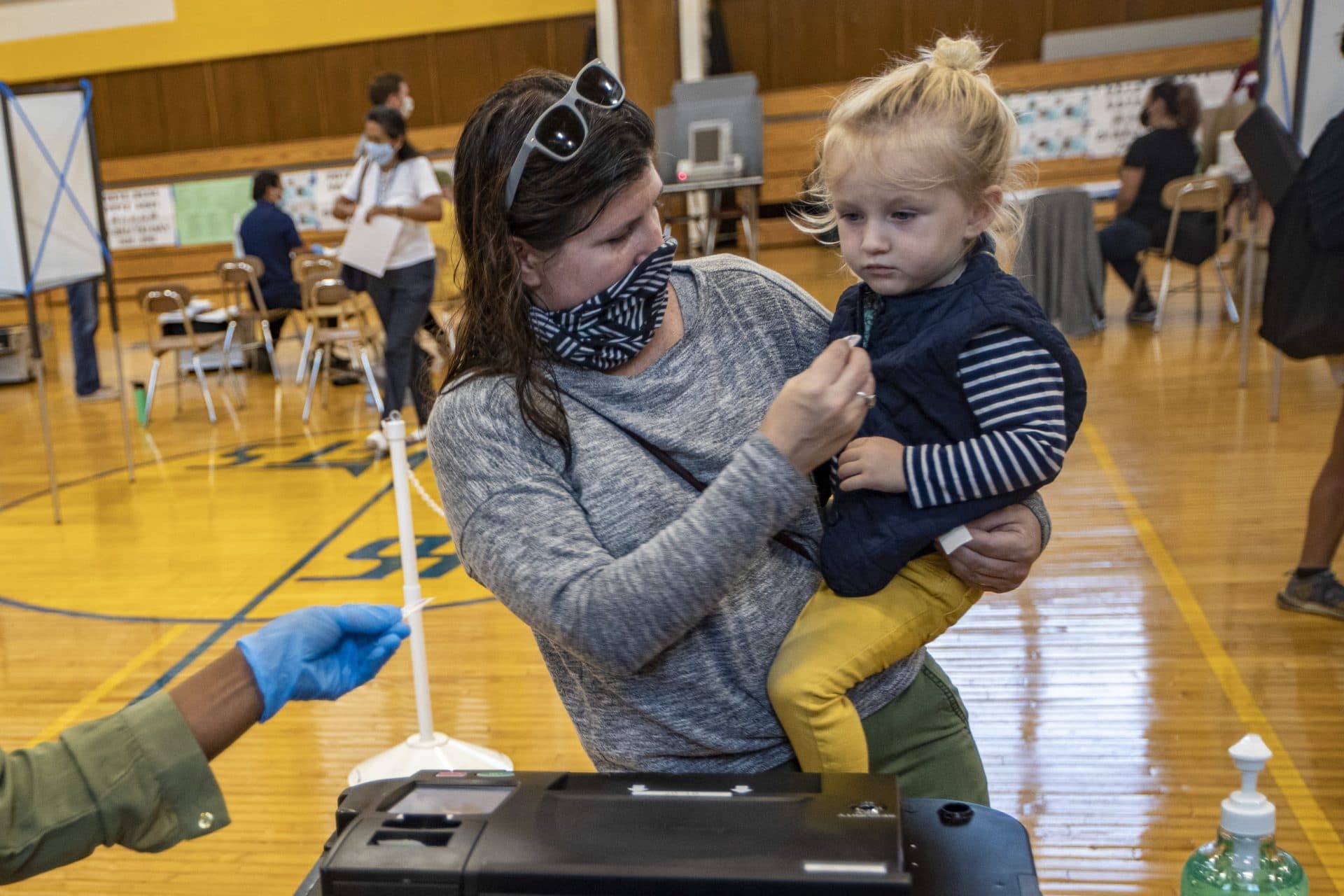 Two-year-old Milo Grady gets a voting sticker from her mother after she cast her ballot to vote at Ward 1 in East Boston High School. (Jesse Costa/WBUR)