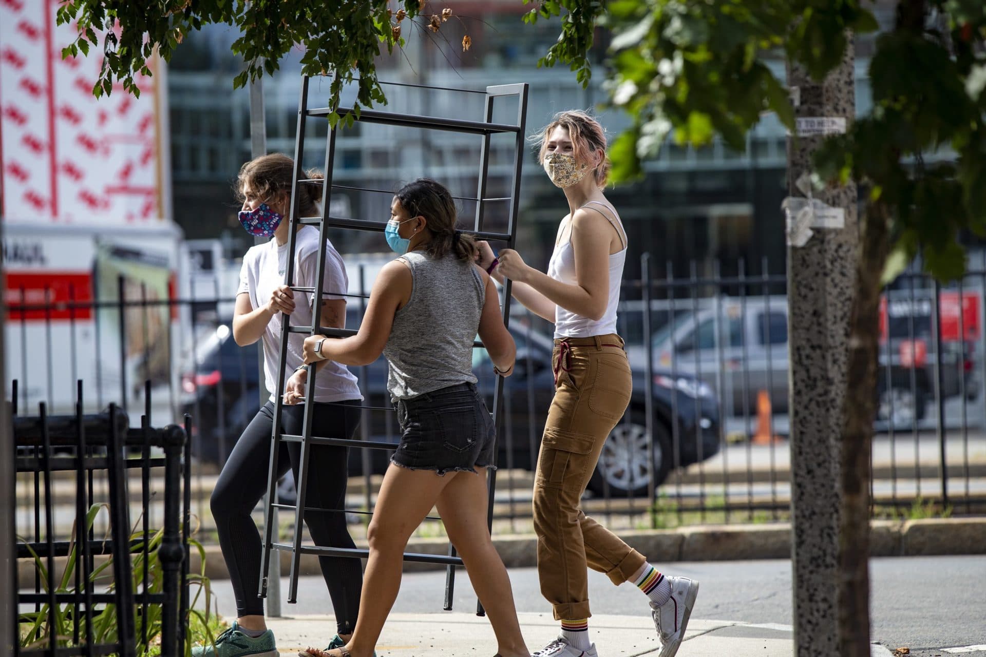 A group of students walks down Commonwealth Avenue carrying a bookshelf on moving day. (Jesse Costa/WBUR)