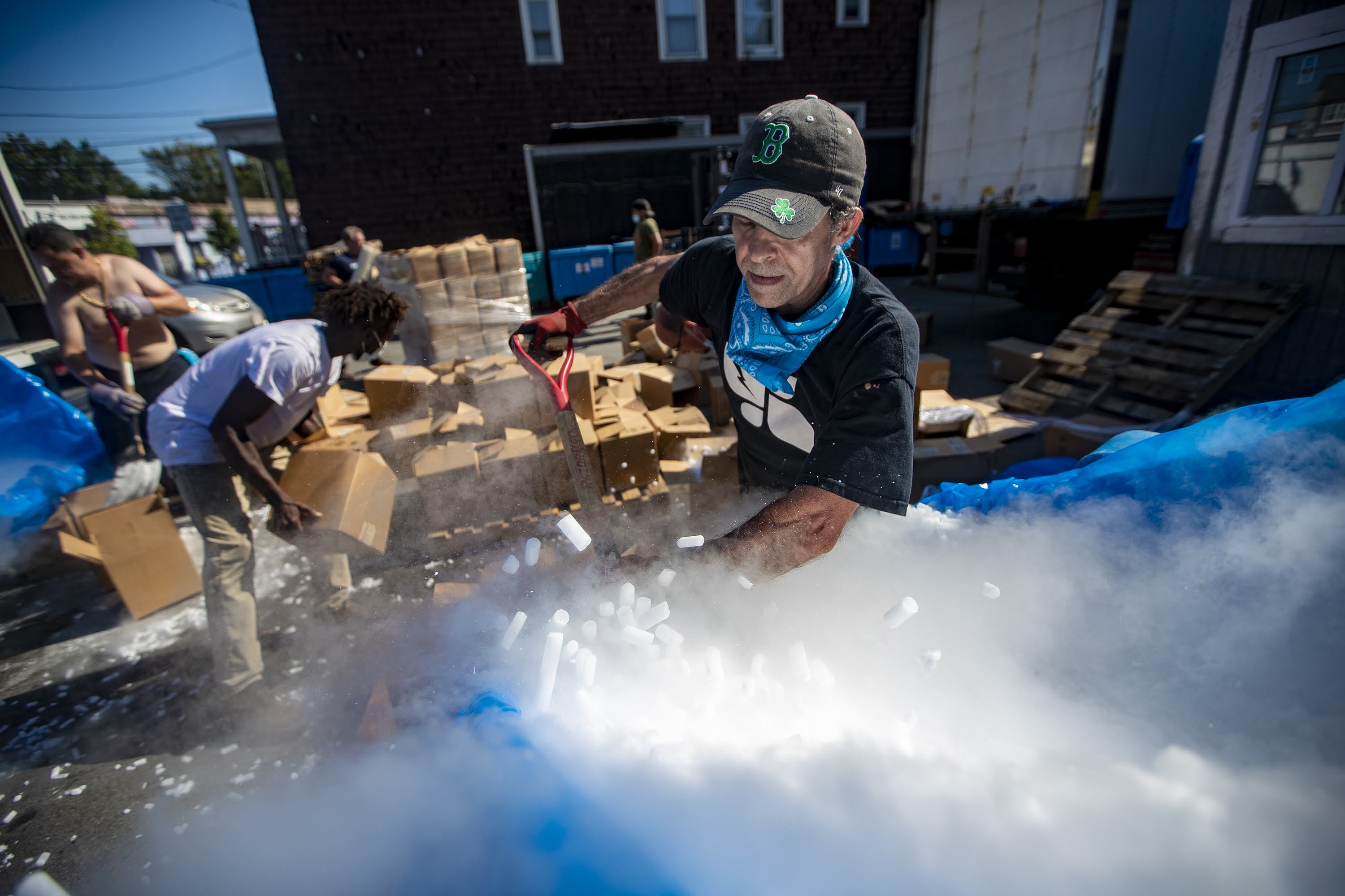 Workers at Acme Ice Company in Cambridge load 50,000 pounds of dry ice into boxes to be shipped out to various pharmaceutical companies in the area for storing vaccine samples of COVID-19. (Jesse Costa/WBUR)