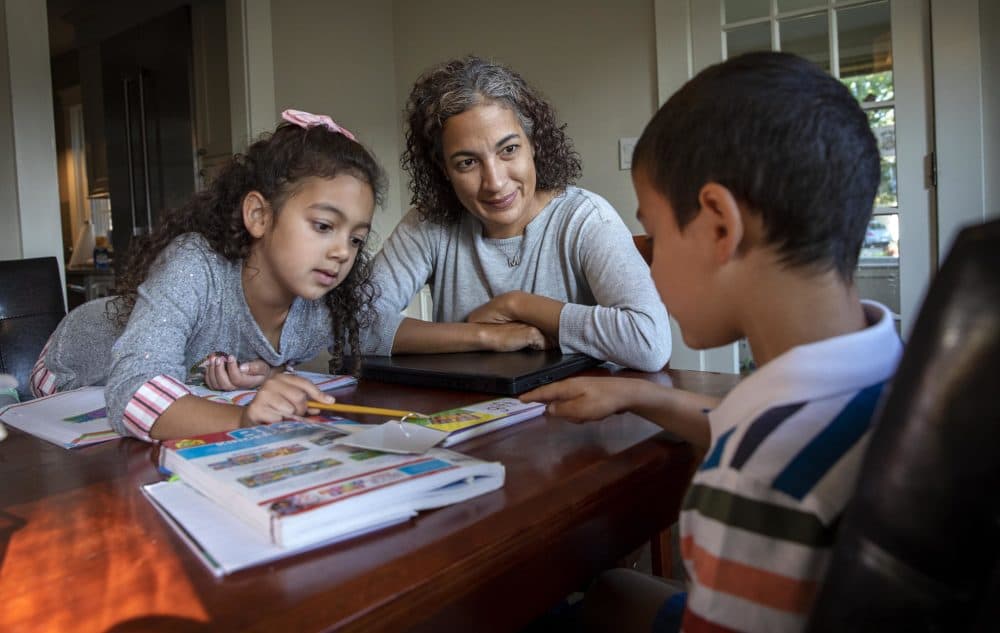 Dr. Maria Diaz, an internist at the Greater Lawrence Family Health Center, helps her children, Noa, 7, and Ethan, 5, with their schoolwork. (Robin Lubbock/WBUR)