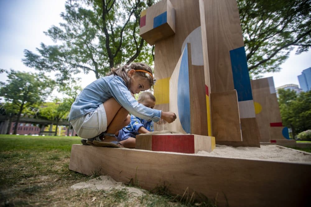 Six-year-old Sophia Angelov of Revere picks up a handful of sand as she plays on The Shape of Play, a new public art installation by artist Sari Carel, in Christopher Columbus Waterfront Park in the North End. (Jesse Costa/WBUR)