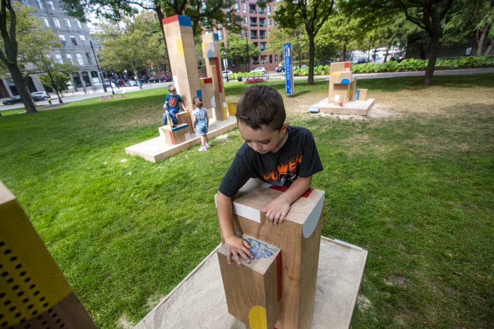 Five-year-old Lucas Boulrice brushes sand off of one of the structures. (Jesse Costa/WBUR)