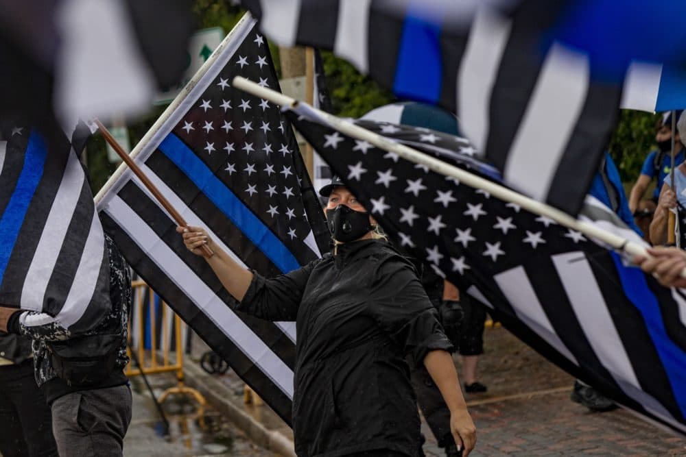 A Back the Blue supporter waves a flag in a sea of thin blue line flags during opposing rallies with Black Lives Matter counterprotesters in front of Arlington City Hall. (Jesse Costa/WBUR)